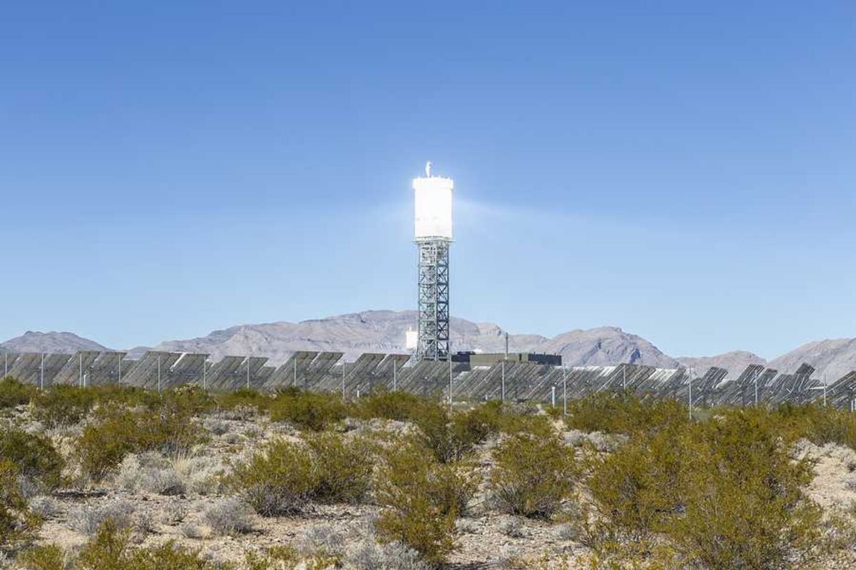 A solar tower above a desert landscape with solar panels
