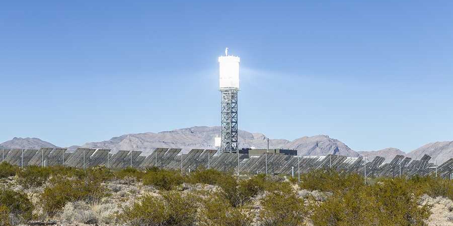 A solar tower above a desert landscape with solar panels