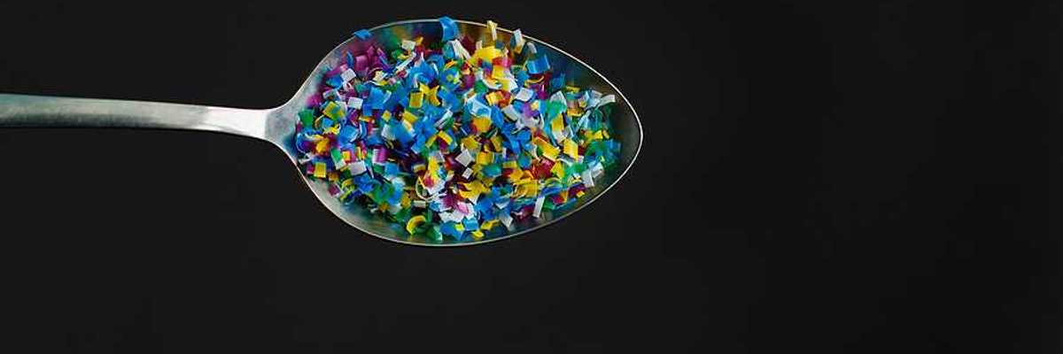 A spoon with microplastics in it on a black background