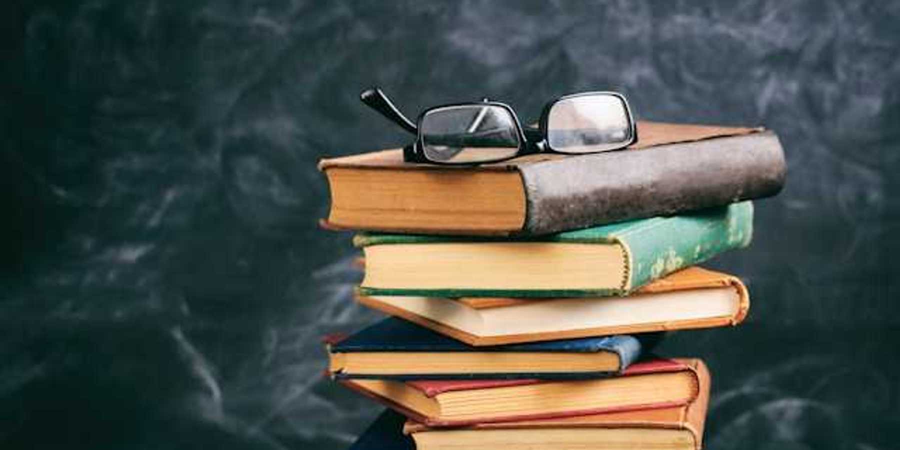 A stack of books with a pair of readers sitting atop it