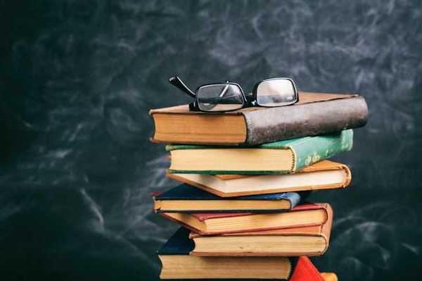 A stack of books with a pair of readers sitting atop it