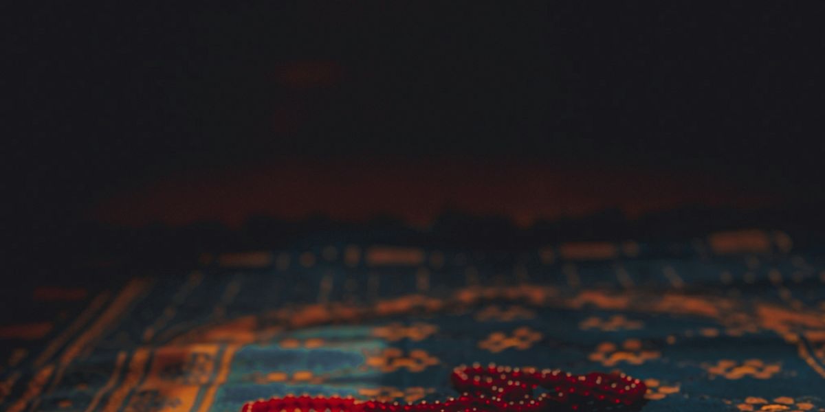 A string of red beads lying on a patterned rug.
