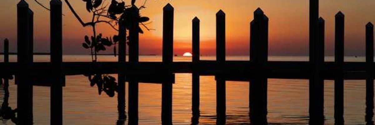 A sunset view of water and a wooden dock