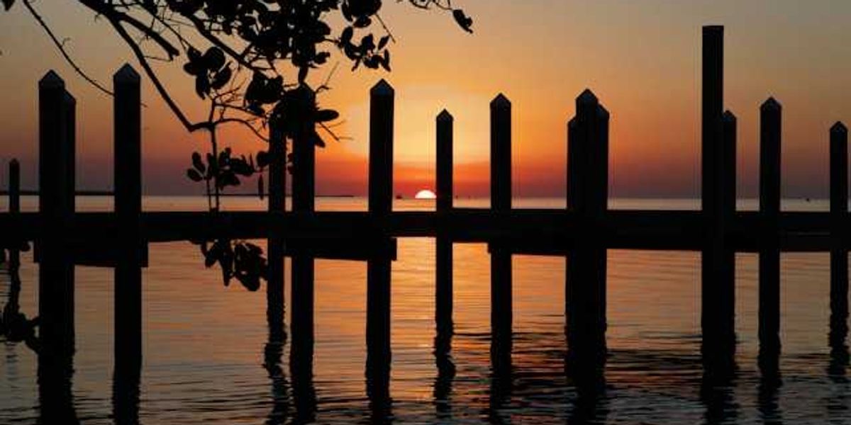 A sunset view of water and a wooden dock