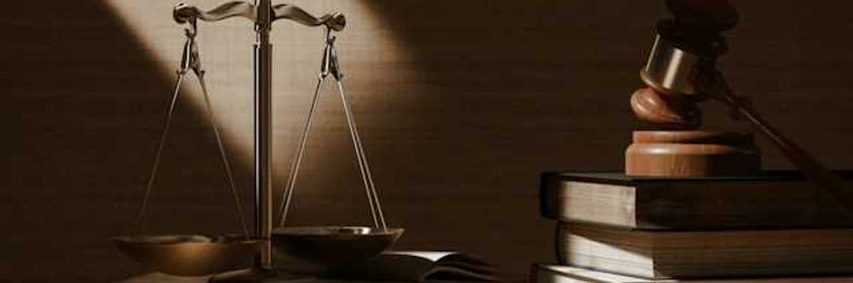 A table with scales of justice and a wooden gavel on top of legal books
