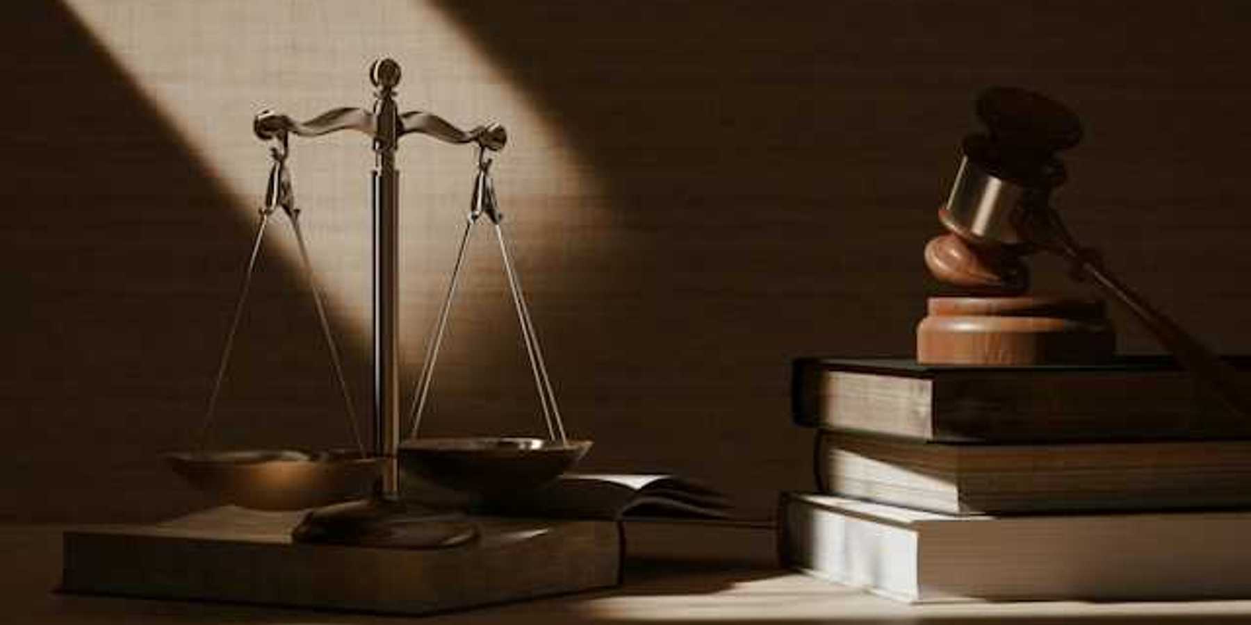 A table with scales of justice and a wooden gavel on top of legal books