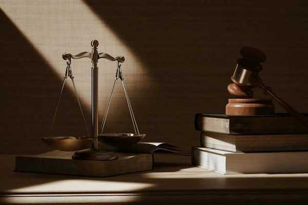 A table with scales of justice and a wooden gavel on top of legal books