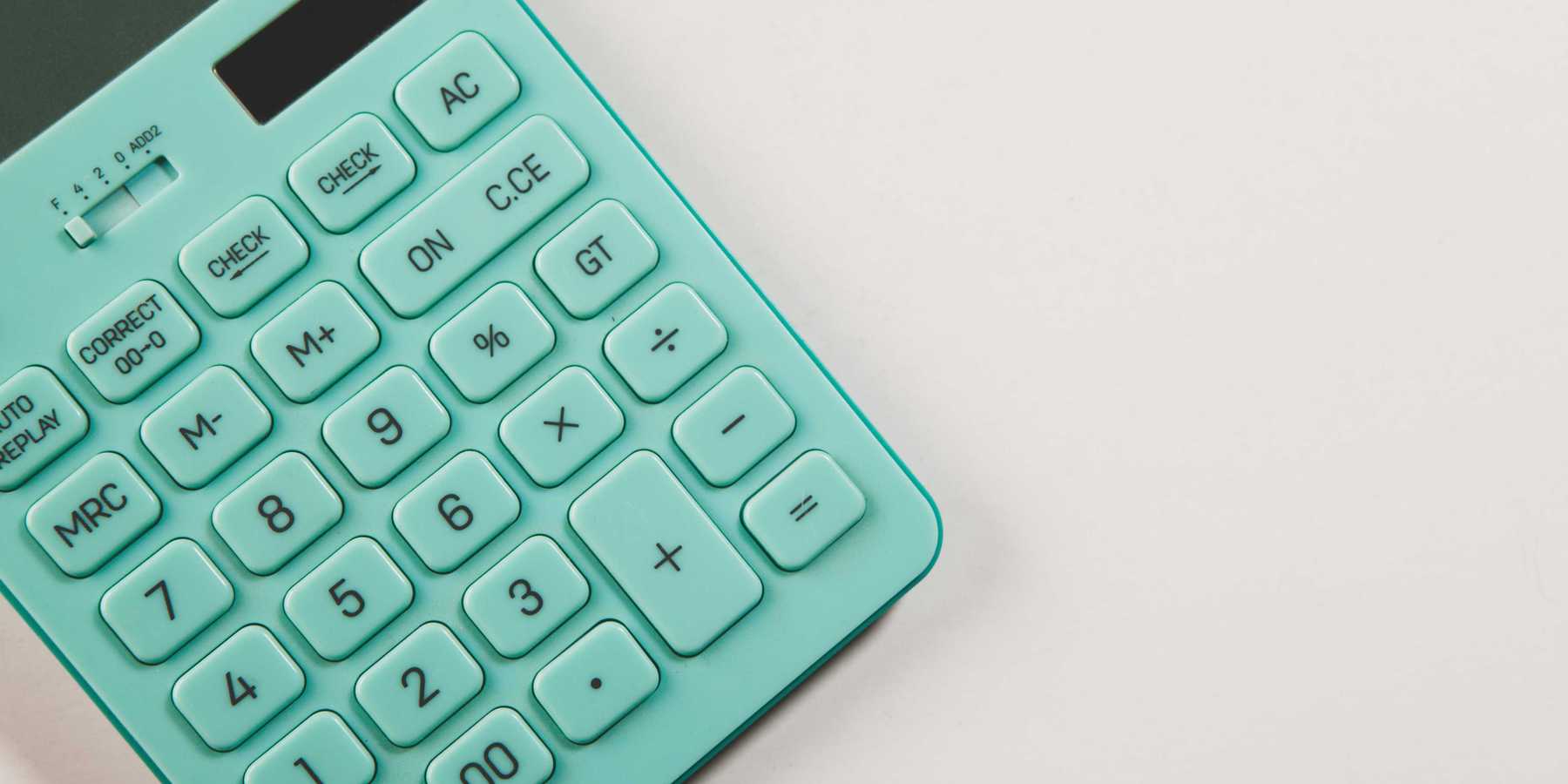 A teal calculator rests on a white surface.