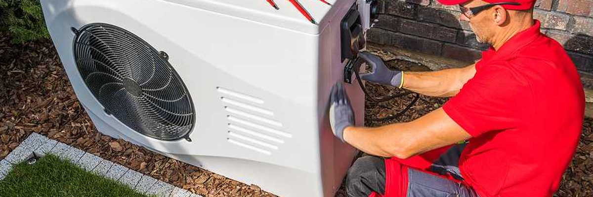 A technician working on a heat pump outside a house