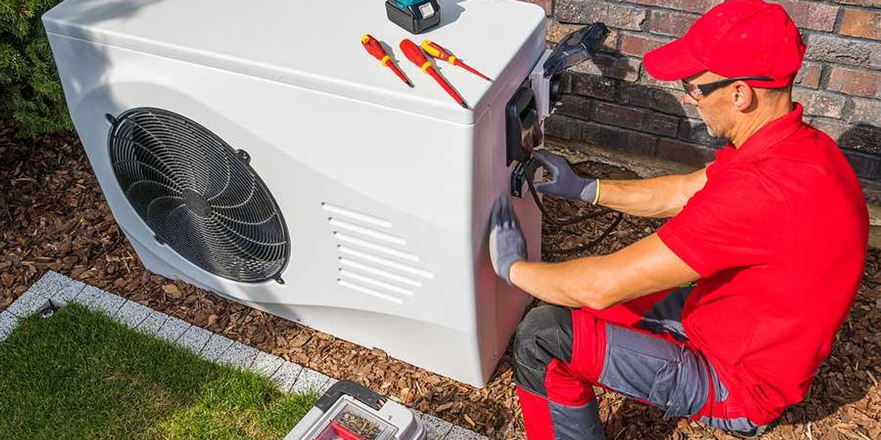 A technician working on a heat pump outside a house