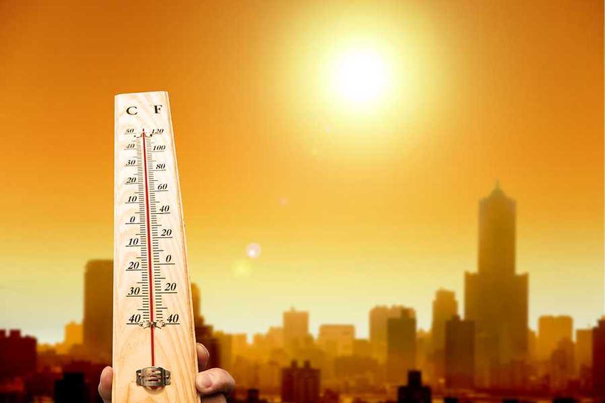 A thermometer showing hot temperatures with the outline of a city in the background