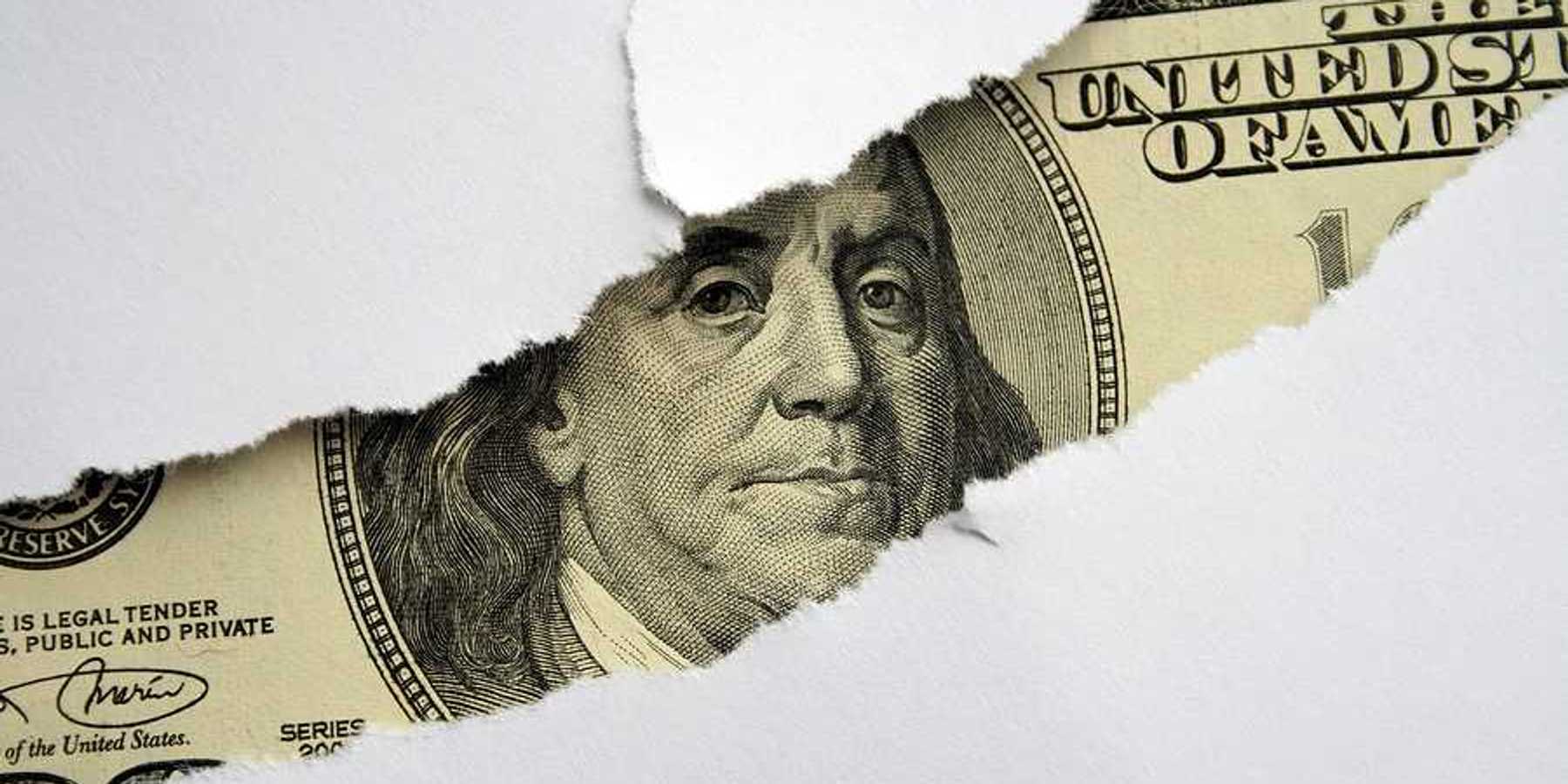 A torn white piece of paper with a $100 bill shown behind it