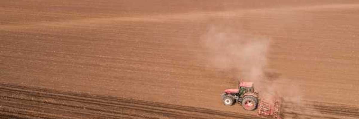 A tractor dragging an implement across a dry farm field