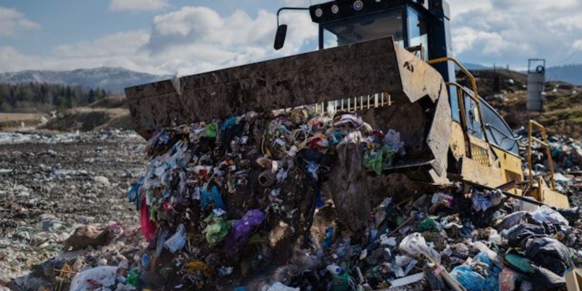 A tractor pushing trash into a pile in a landfill.
