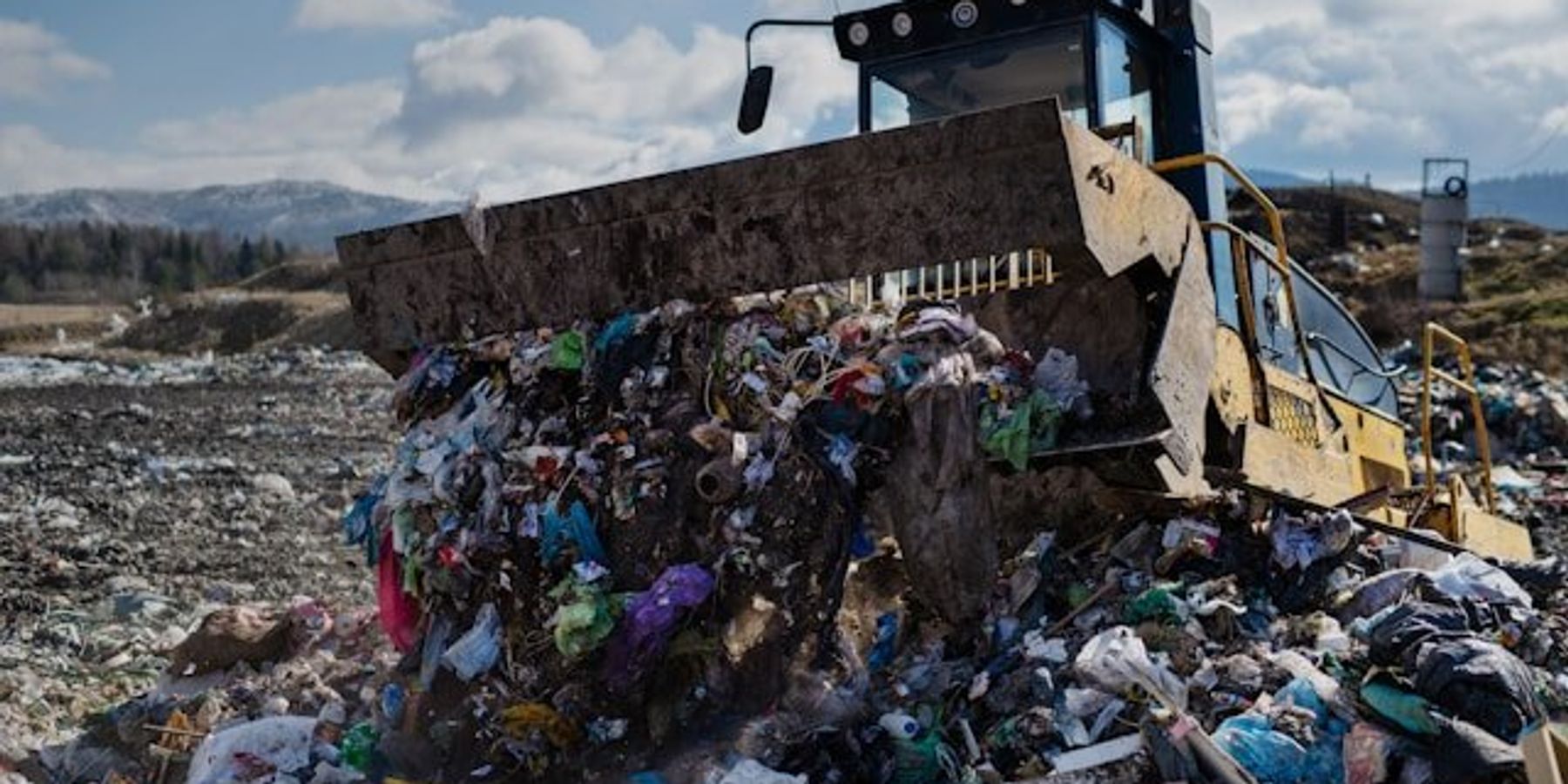 A tractor pushing trash into a pile in a landfill.