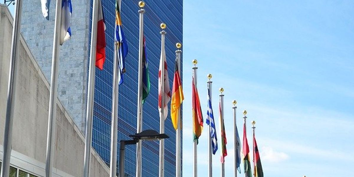A variety of national flags flying in front of a tall building