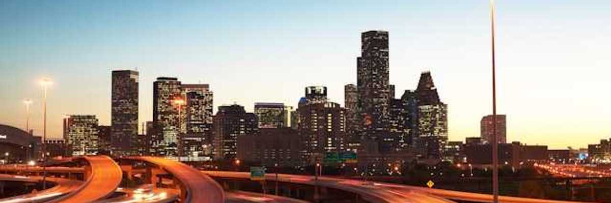 A view at dusk of highways leading into an urban downtown with skyscapers
