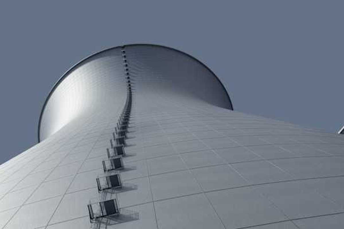 A view from below of a power cooling tower against a blue sky