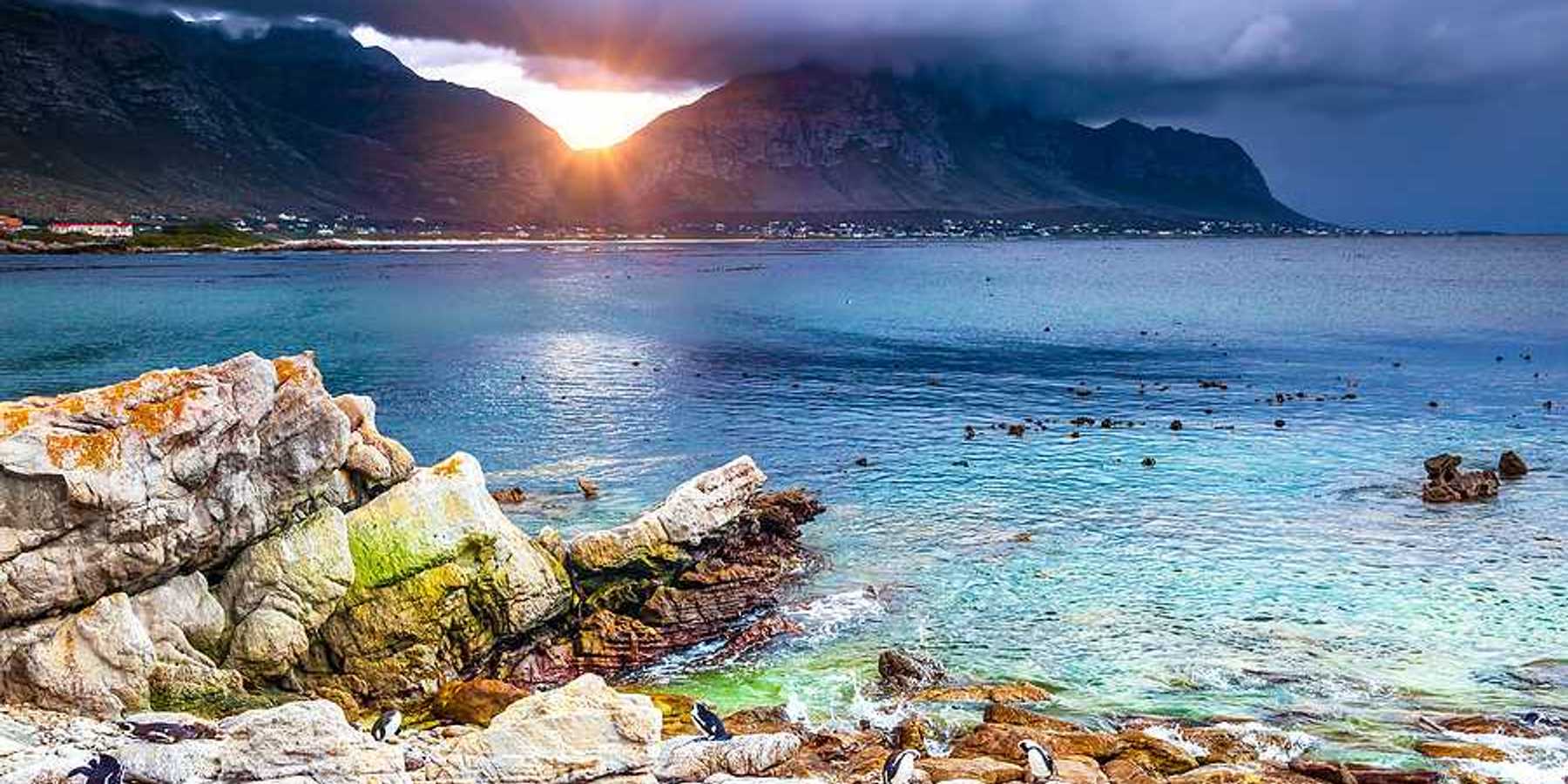 A view of a bay with rocky coastline and mountains in the background