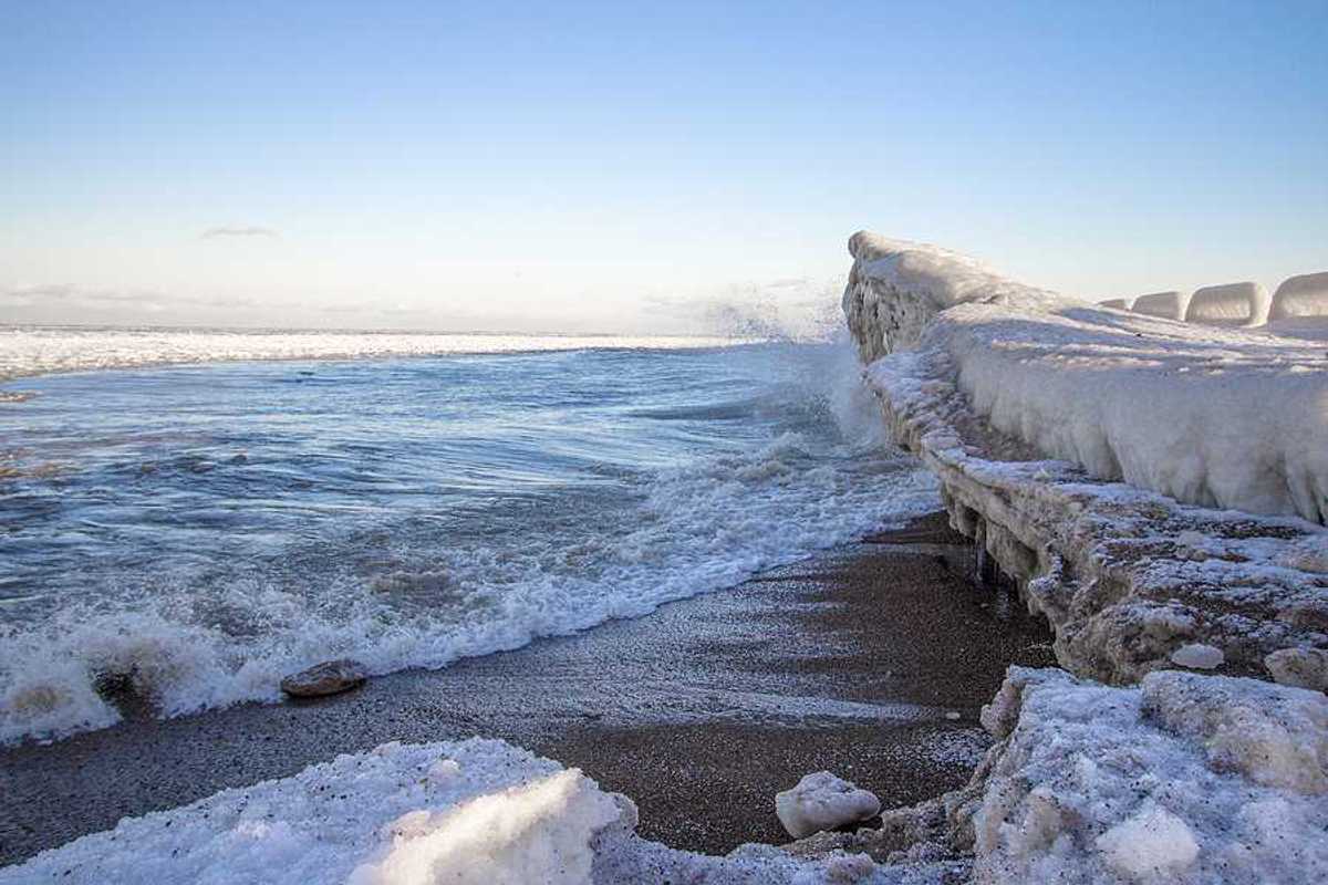 A view of a beach with ice built up on the shore and in the water