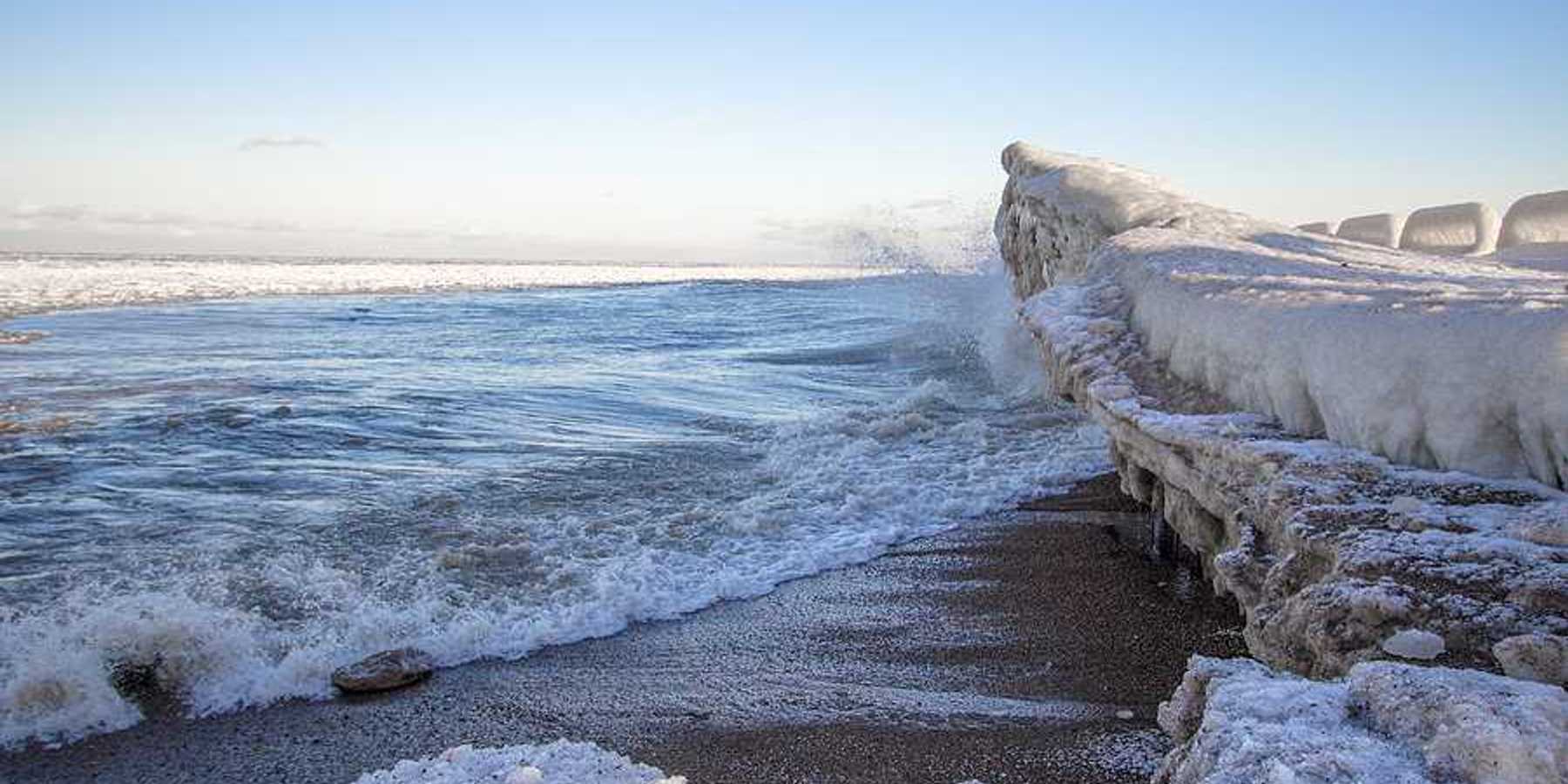 A view of a beach with ice built up on the shore and in the water