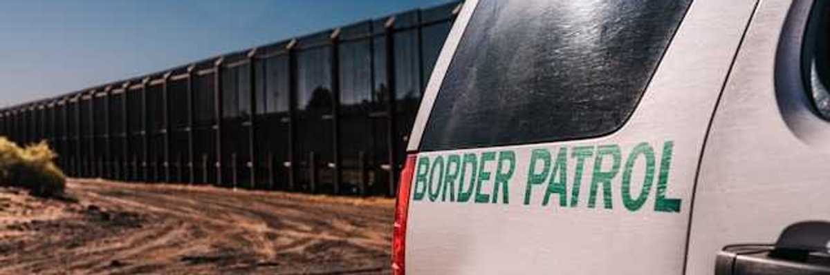 A view of a Border Patrol vehicle next to a tall metal border wall