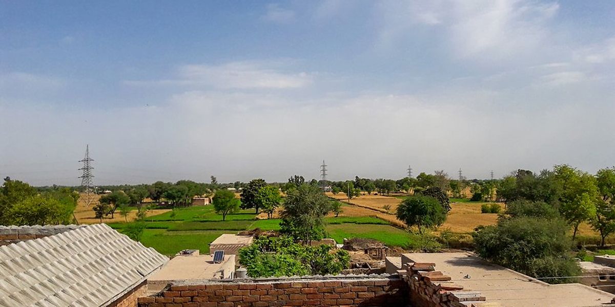 A view of a brick rooftop in with green fields and electric towers in the background
