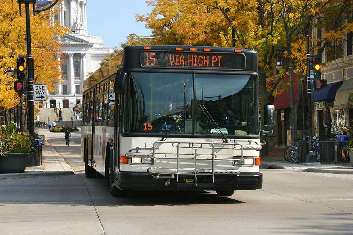 A view of a bus driving down a Madison, WI street with the capitol building in the background