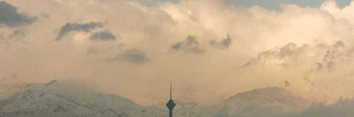 A view of a city mineret with snowy mountains in the background