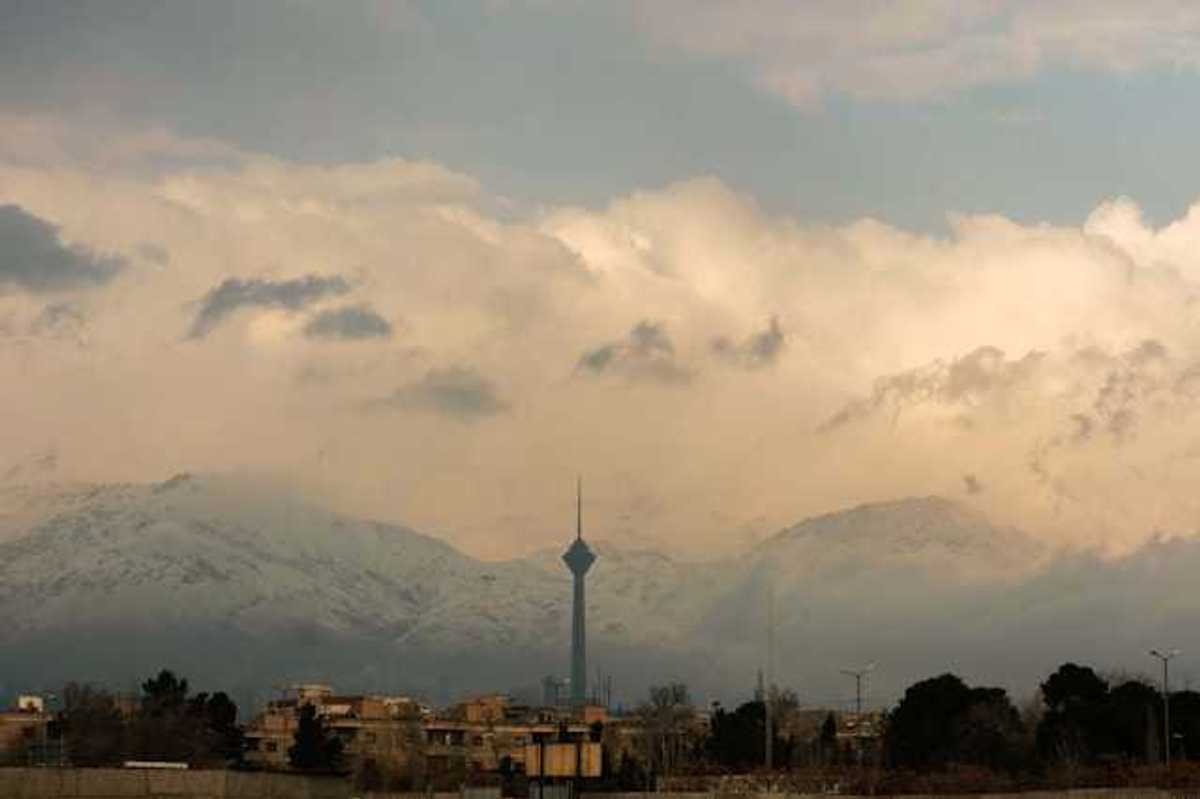 A view of a city mineret with snowy mountains in the background