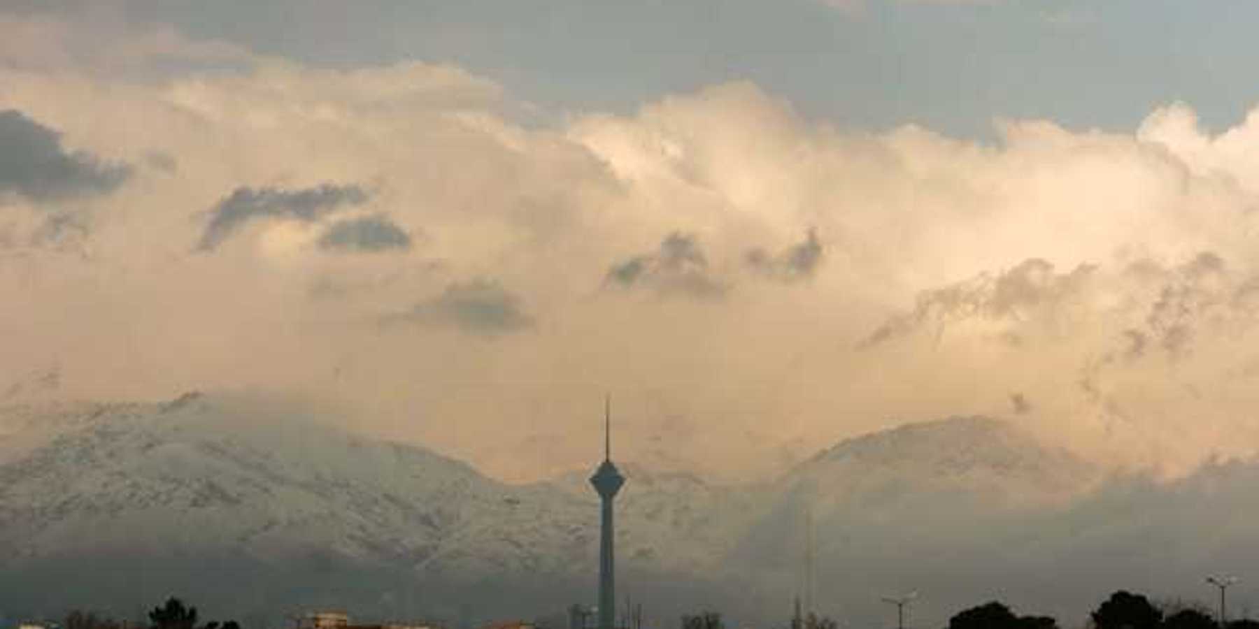 A view of a city mineret with snowy mountains in the background