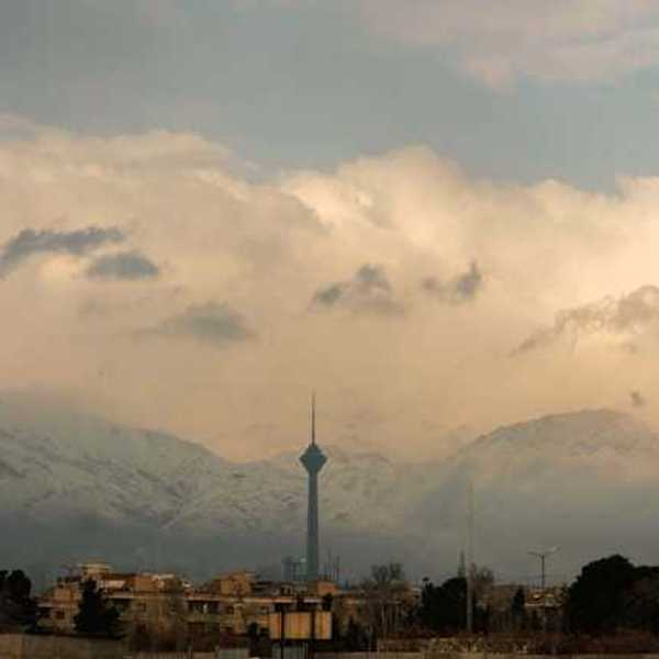 A view of a city mineret with snowy mountains in the background