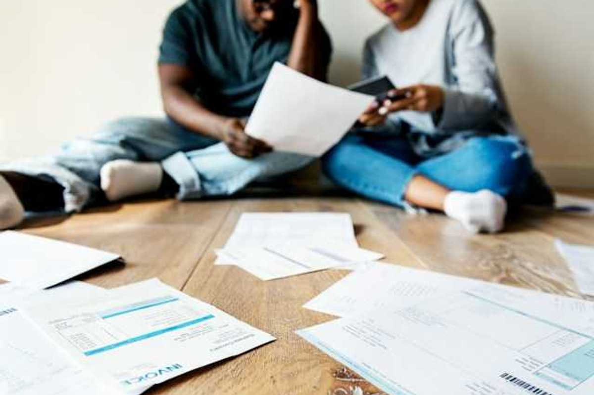 A view of a couple sitting on the floor looking through bills