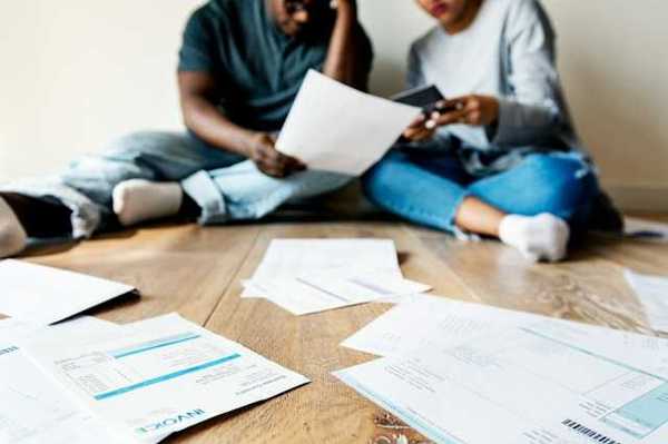 A view of a couple sitting on the floor looking through bills