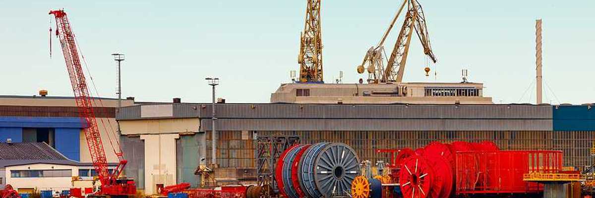 A view of a dock with giant spools of cable and cranes