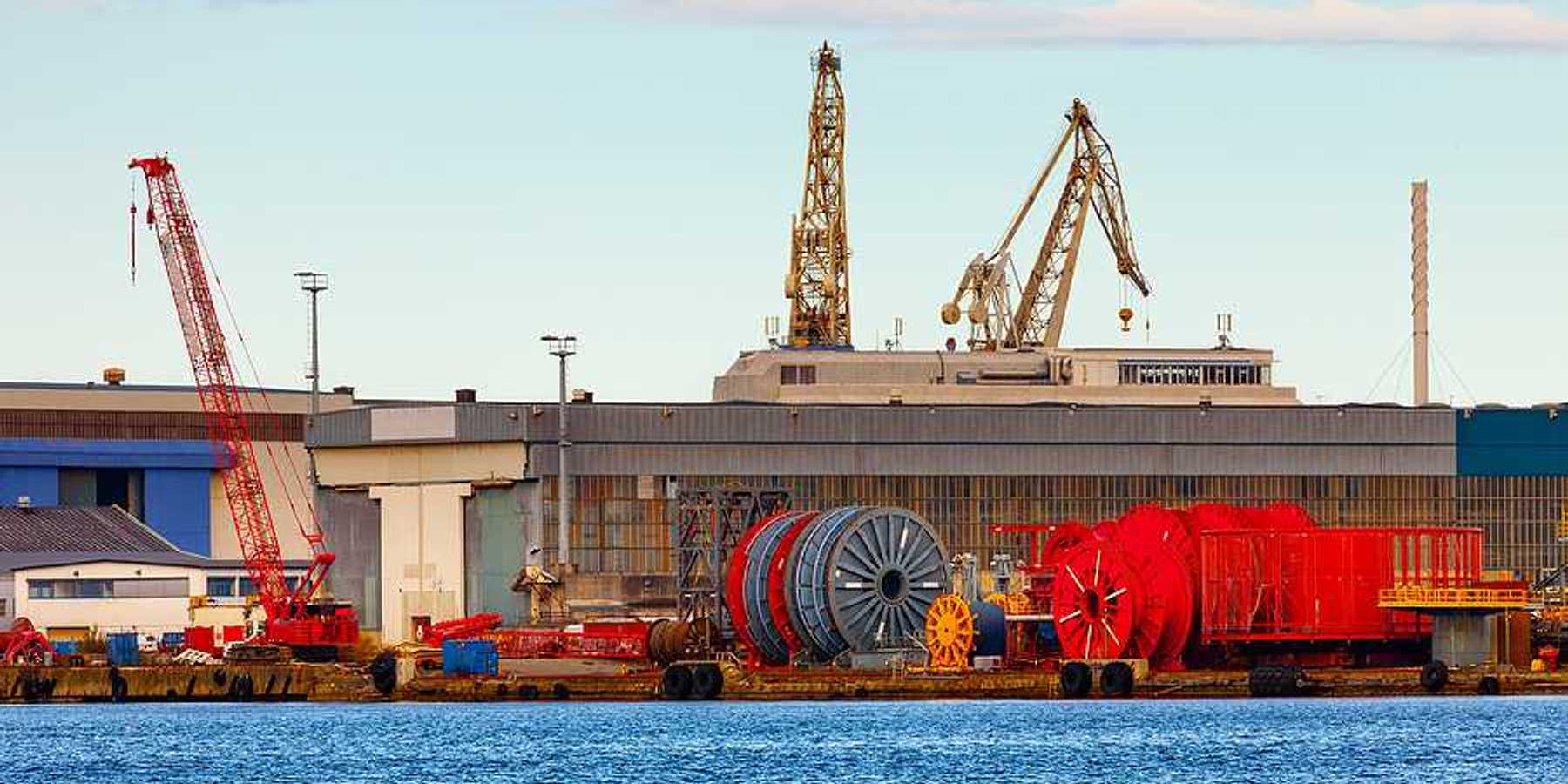 A view of a dock with giant spools of cable and cranes