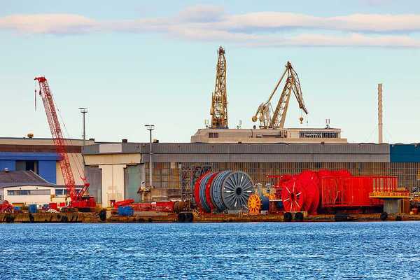 A view of a dock with giant spools of cable and cranes