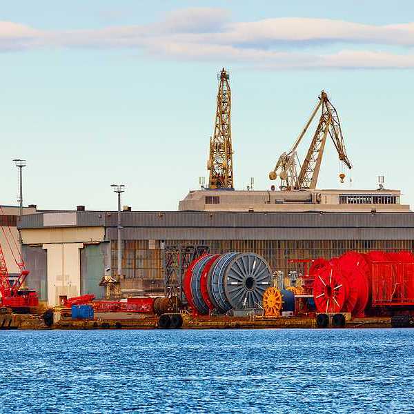 A view of a dock with giant spools of cable and cranes