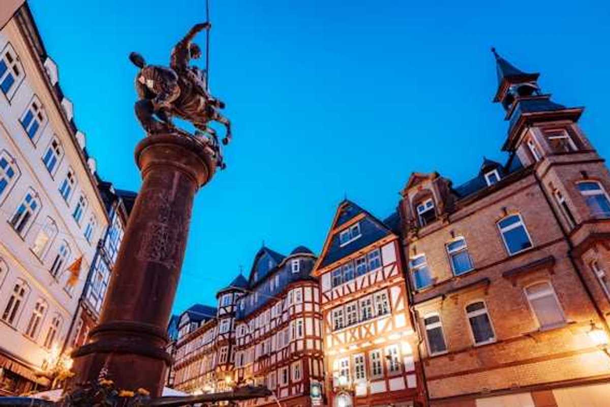 A view of a European square with half-timbered houses and a status of a man on a horse