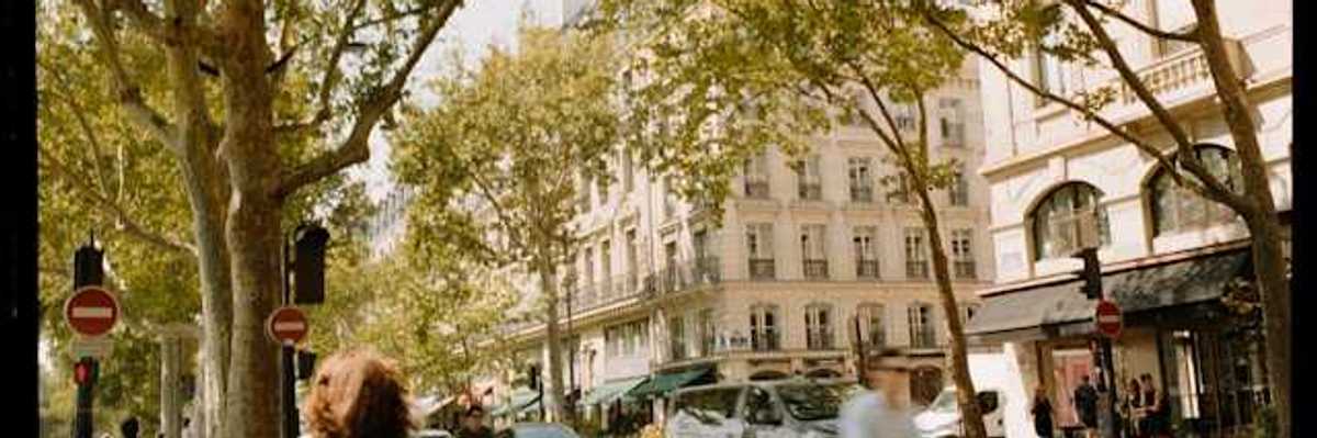 A view of a European street with trees, buildings and people walking and on bikes