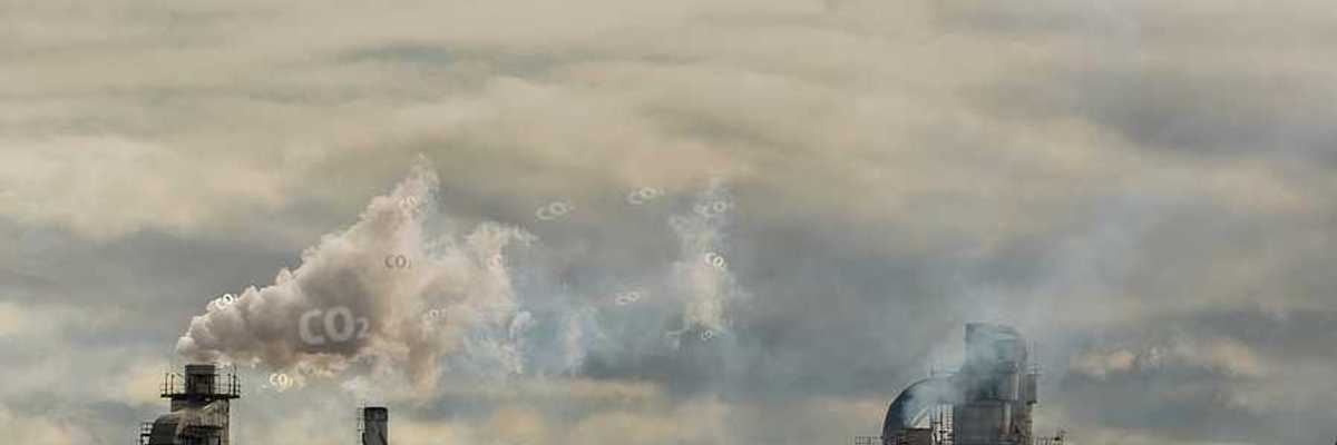 A view of a factory with smoke emitting from the smokestacks into a gray sky