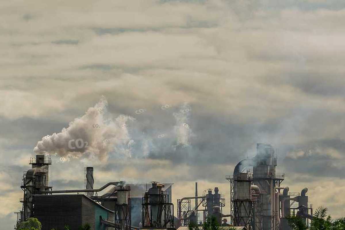A view of a factory with smoke emitting from the smokestacks into a gray sky
