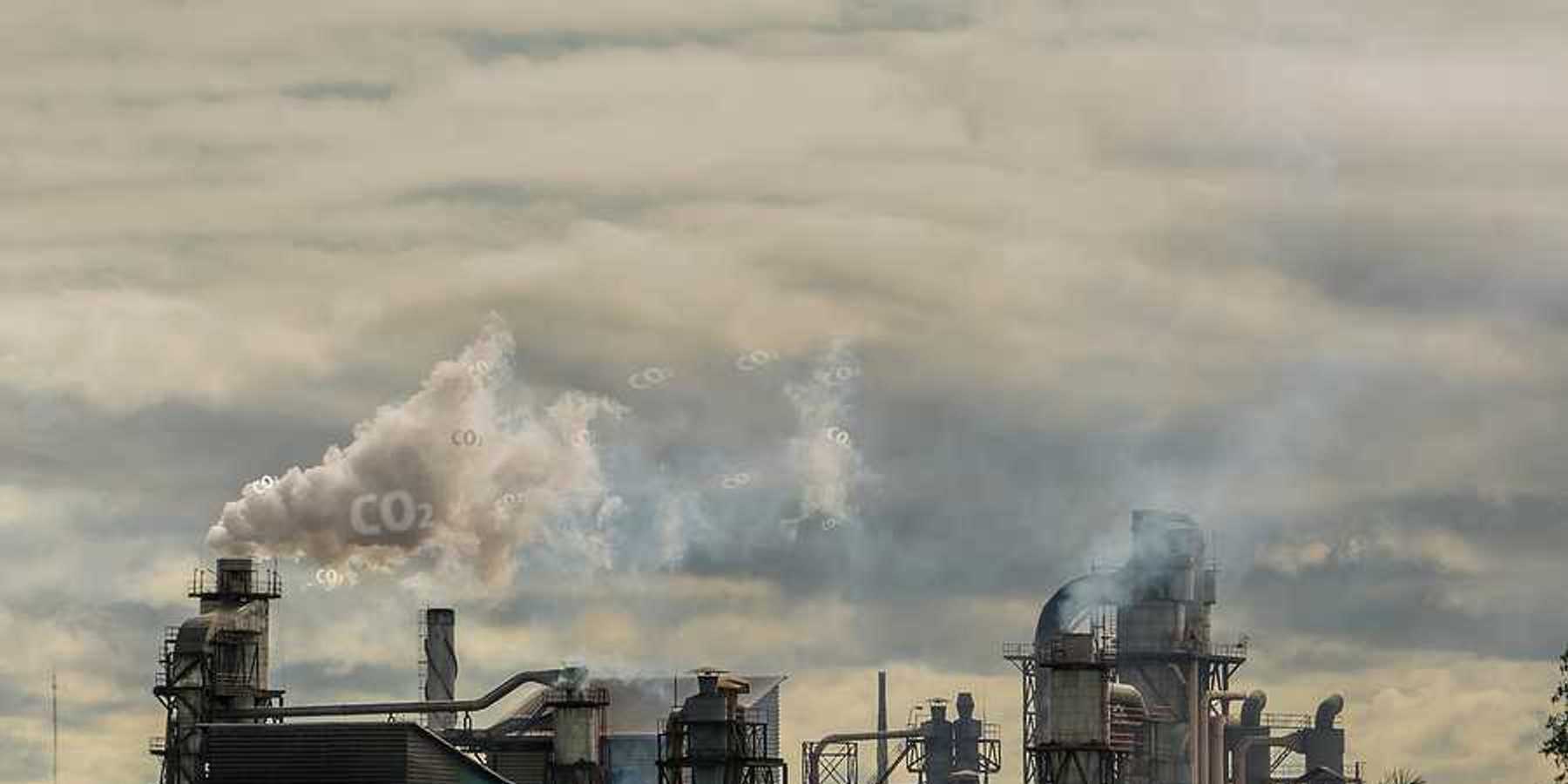 A view of a factory with smoke emitting from the smokestacks into a gray sky