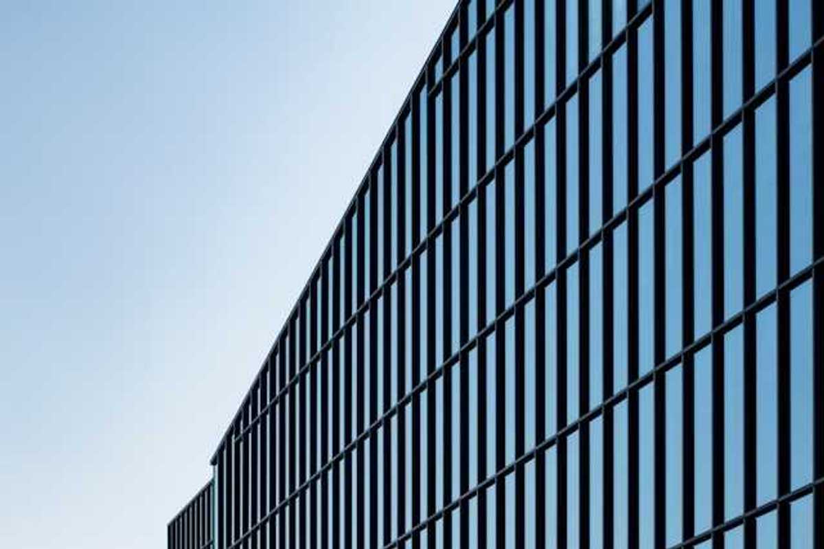 A view of a glass office building with blue sky behind it