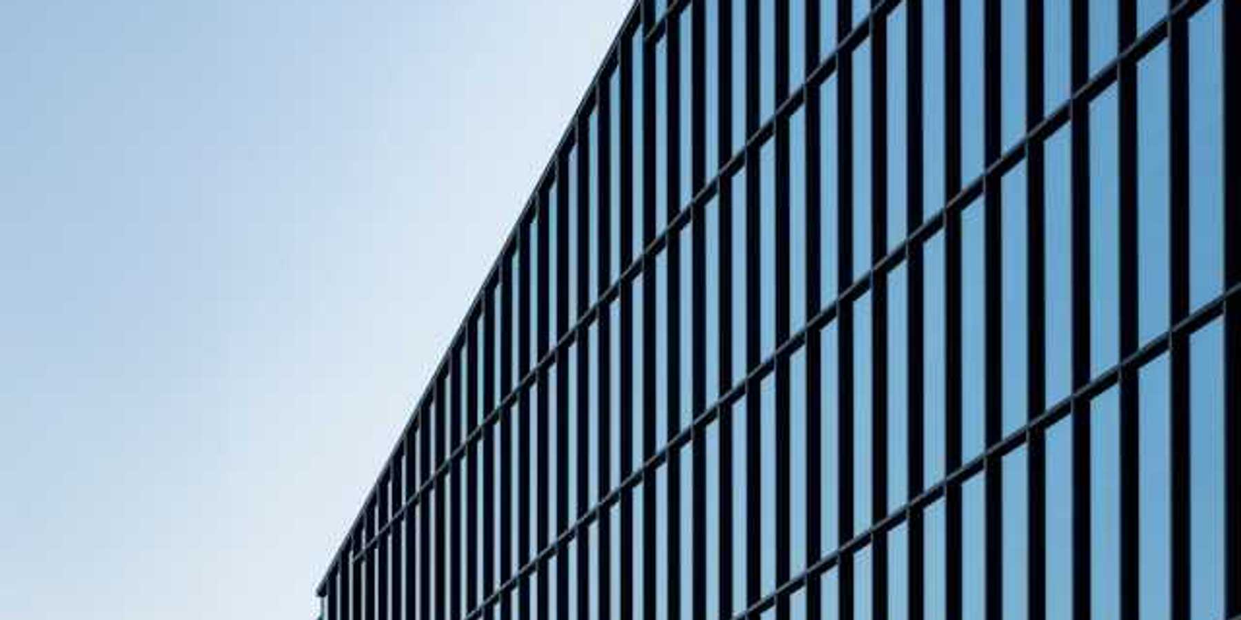 A view of a glass office building with blue sky behind it