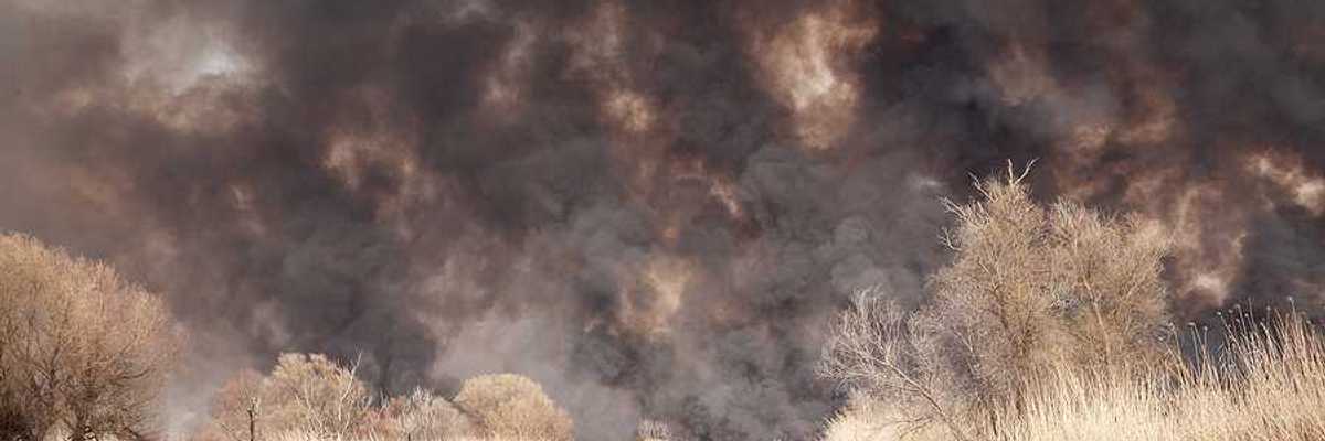 A view of a lake with billowing wildfire smoke in the background