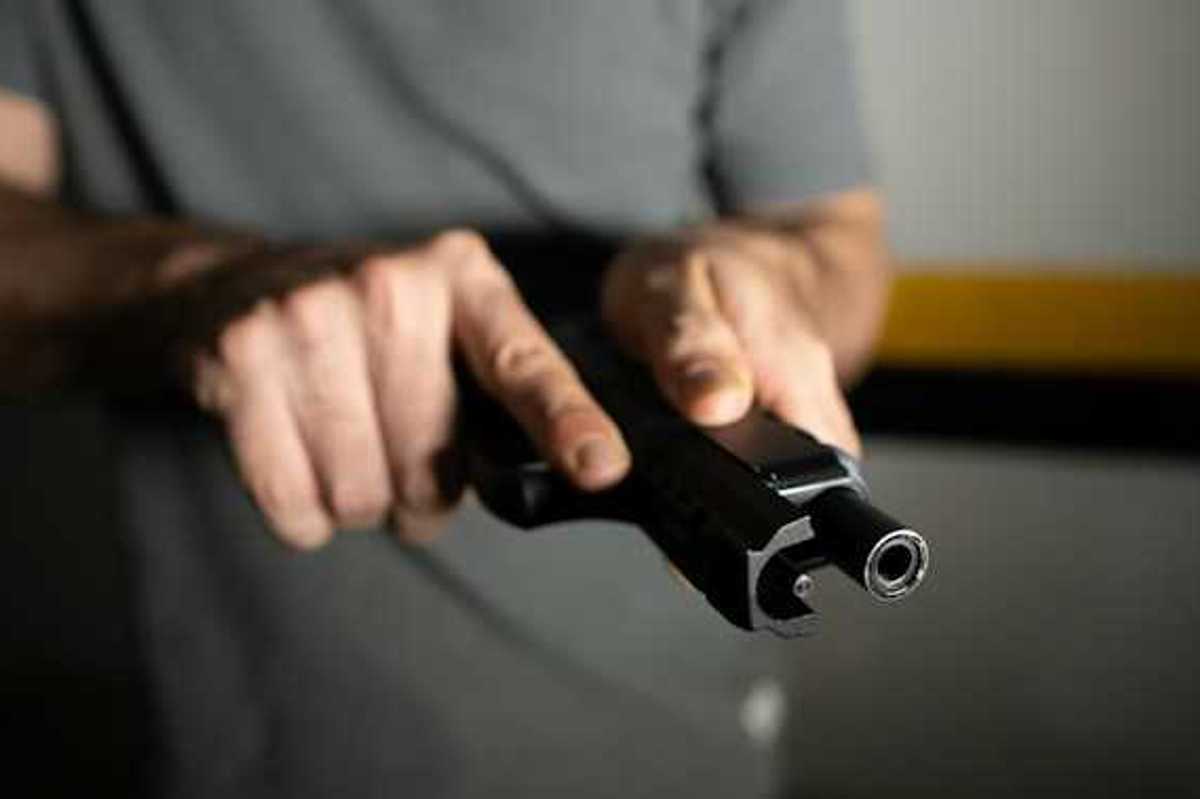 A view of a man's hand holding a black gun