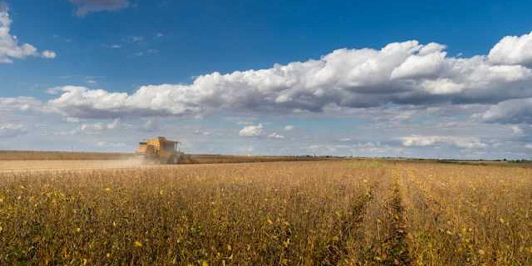 A view of a prairie farm field with a tractor in the distance