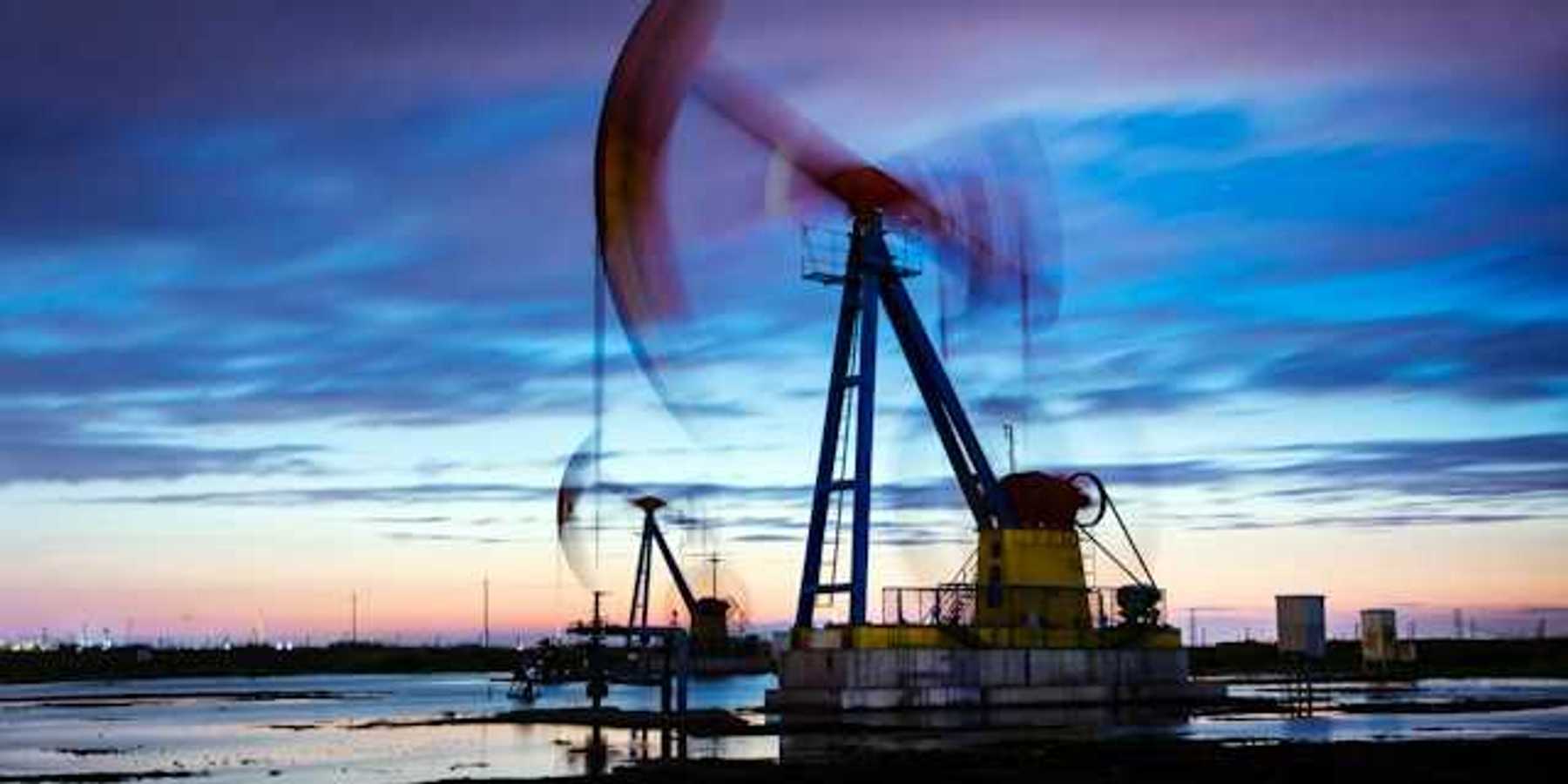 A view of a pump jack drilling for oil with the sunset in the background