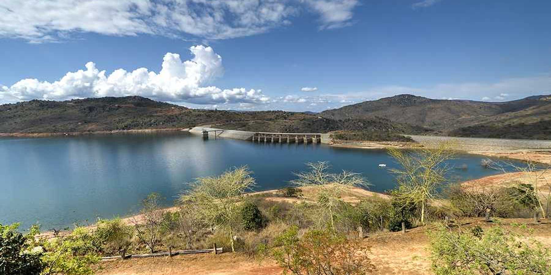 A view of a reservoir and dam with dry land surrounding it